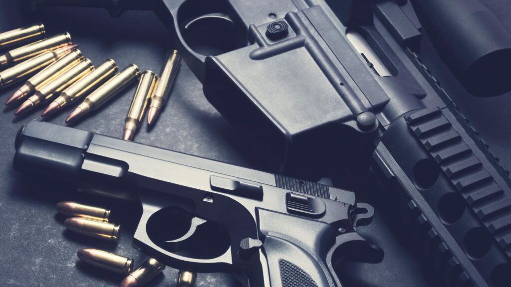 pistol and rifle displayed with ammo on table.
